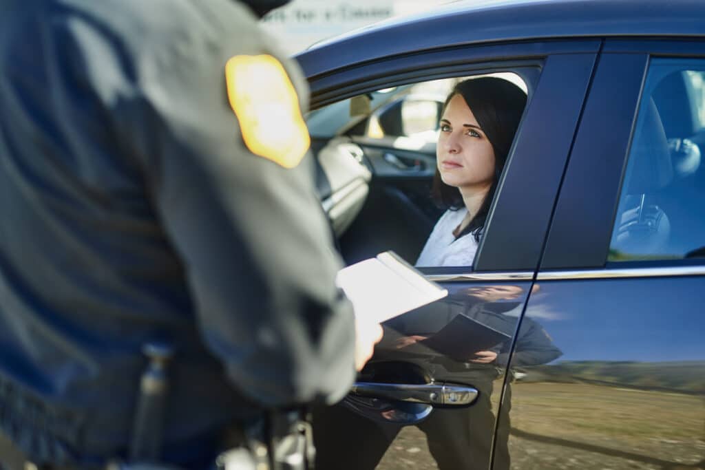 Cropped shot of an unrecognizable male traffic officer issuing a ticket to a female civilian at a roadblock