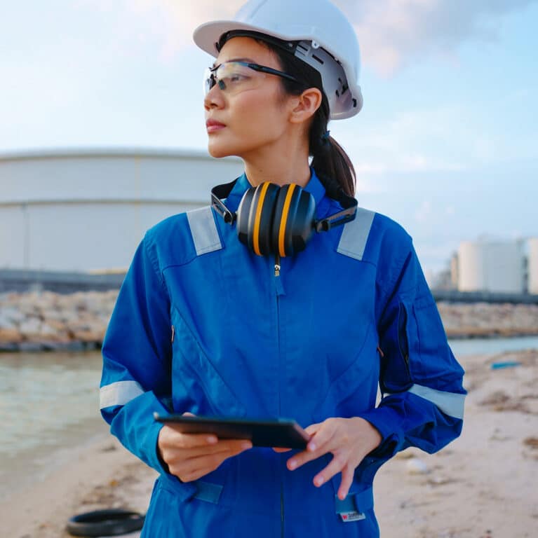 Asian woman Inspection engineers working with laptop of oil factory and gas refinery plant industry at night for inspector safety quality control.