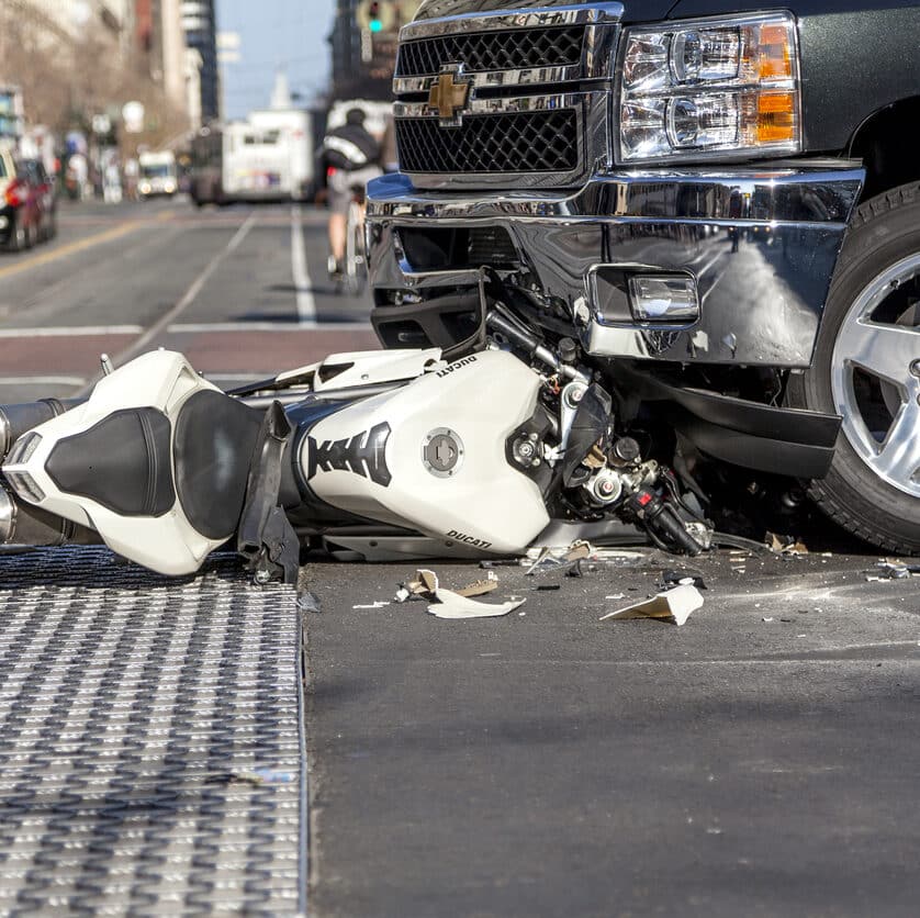 A bad traffic accident between a white Ducati motorcycle and Chevy pickup truck