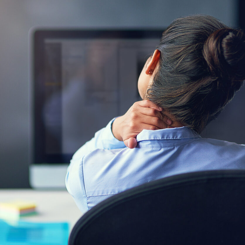 Rearview shot of a businesswoman suffering from neck pain at the office