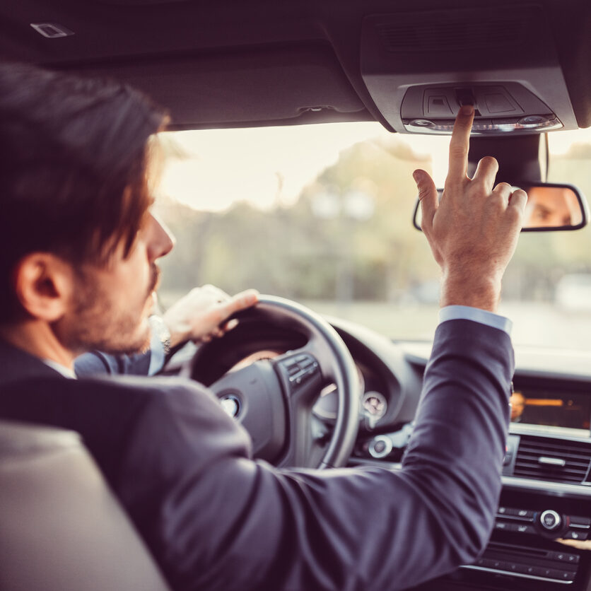 Businessman traveling in car and pressing the car assistance button